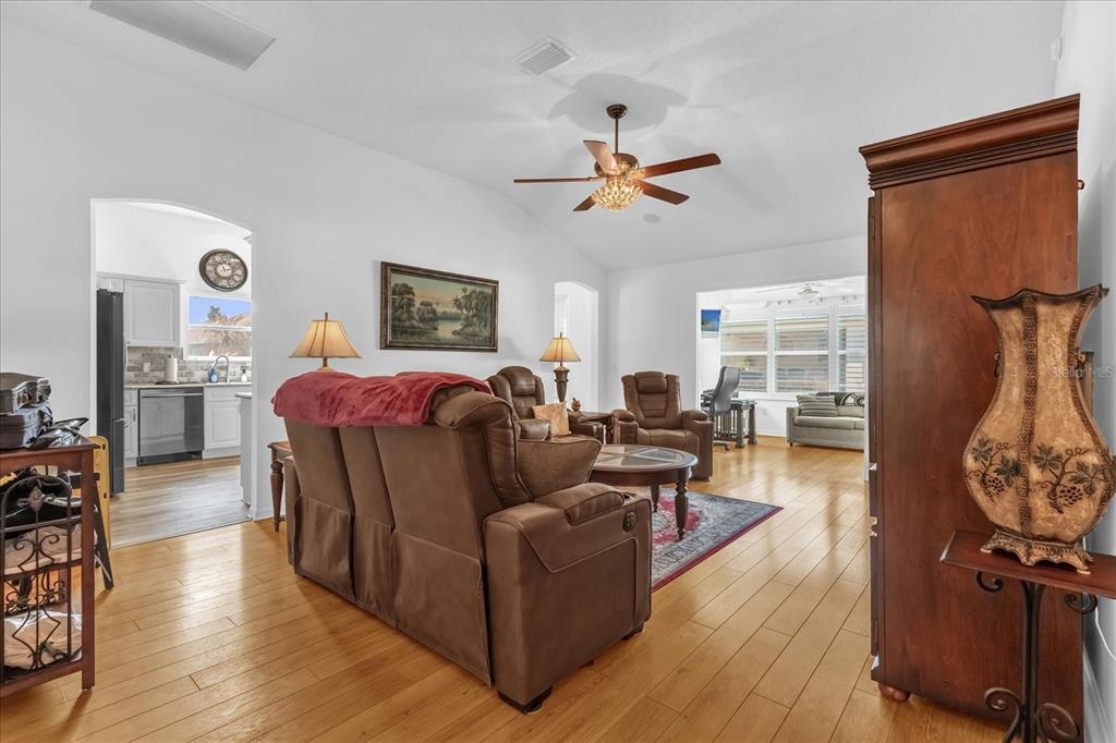 A living room with hardwood floors, brown leather furniture, and a ceiling fan — 1462 PELICAN PATH, THE VILLAGES, FL