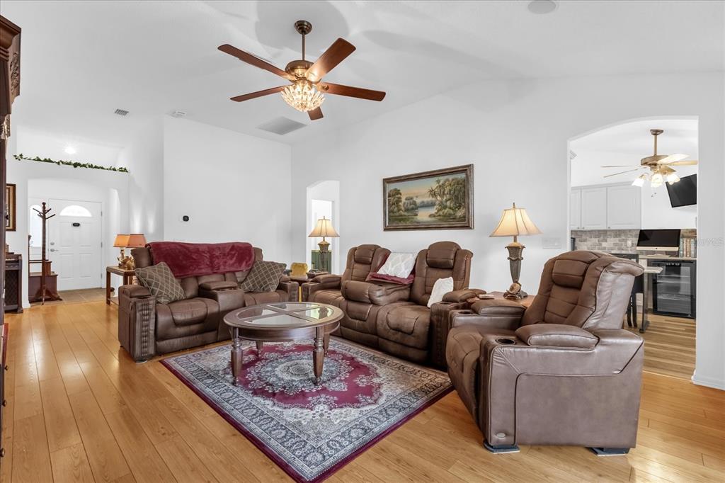 A living room features brown leather furniture, a patterned area rug, and hardwood flooring — 1462 PELICAN PATH, THE VILLAGES, FL