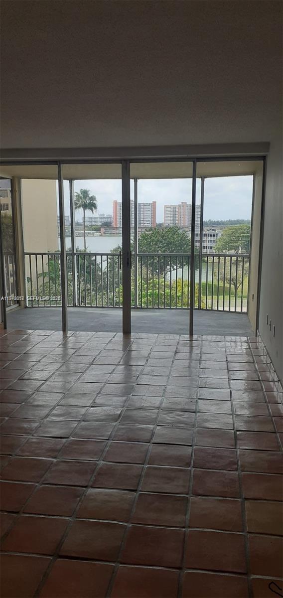 A screened-in balcony overlooks a swimming pool, palm trees, and nearby apartment buildings at night — 1750 NE 191st St # 3, Miami FL 33179, MIAMI, FL
