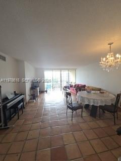 A living and dining area features tile flooring, a chandelier, and a balcony view — 1750 NE 191st St # 3, Miami FL 33179, MIAMI, FL