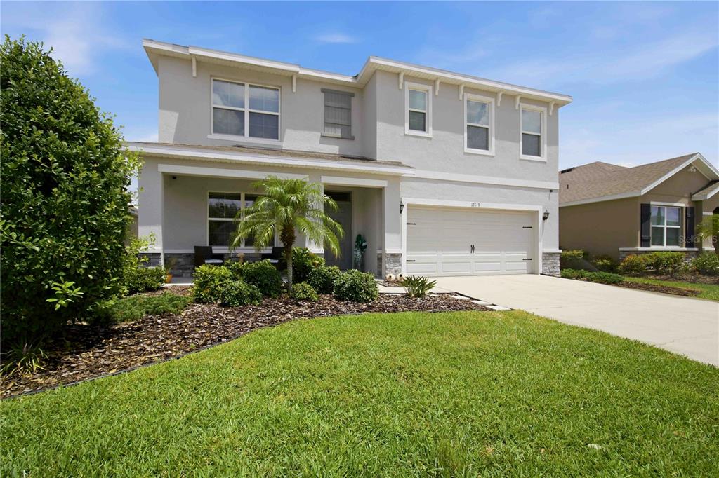 A two-story suburban house with a light gray exterior, a two-car garage, and a lawn — 17119 HARVEST MOON WAY, BRADENTON, FL