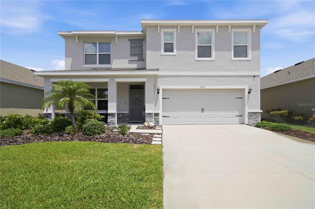 A two-story suburban house with a gray stucco exterior, a two-car garage, and landscaping — 17119 HARVEST MOON WAY, BRADENTON, FL