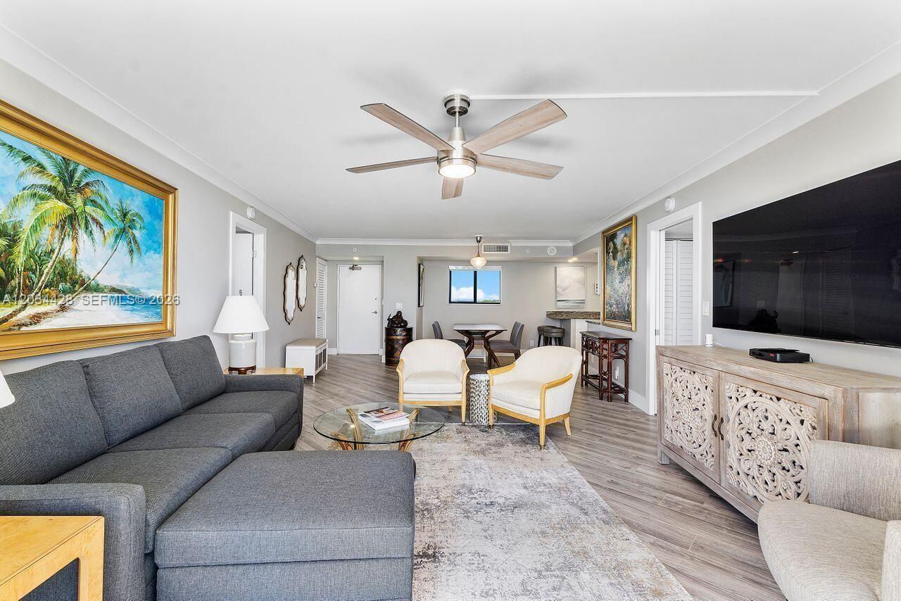 A living room features a grey sectional sofa, two armchairs, and a large wall-mounted television — 200 Ocean Trail Way # 602, Jupiter FL 33477, JUPITER, FL