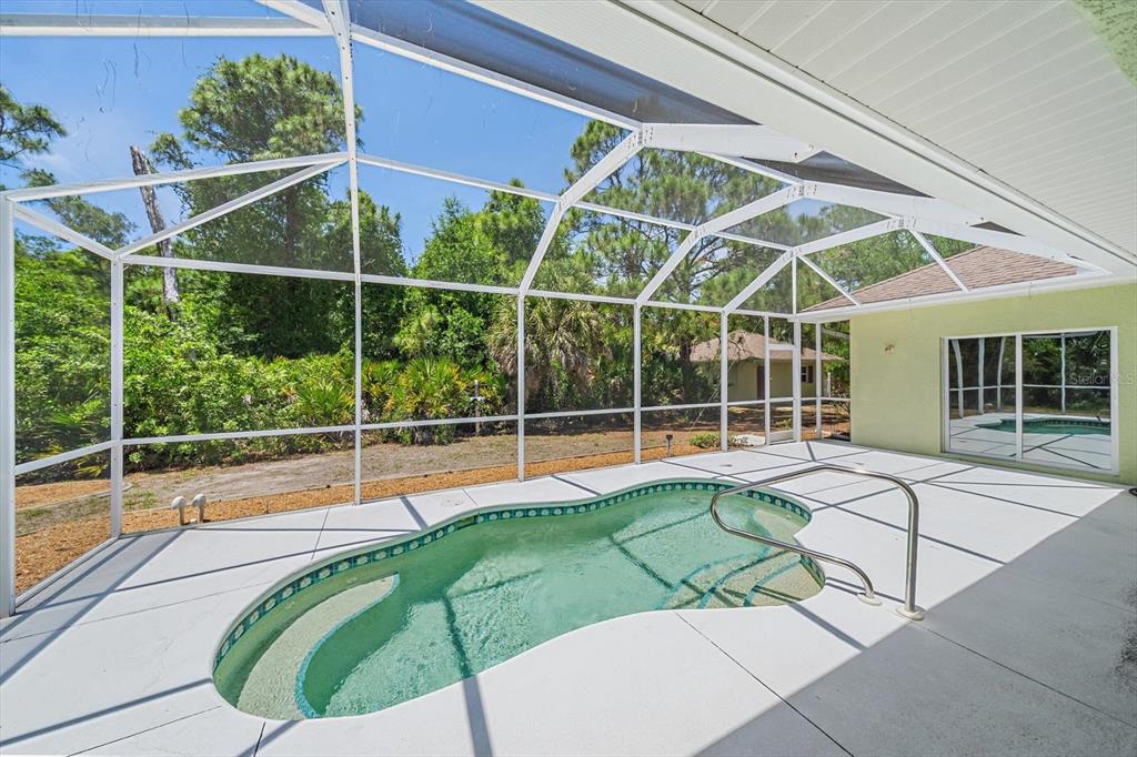 A screened-in patio features a small, kidney-shaped swimming pool with a metal handrail — 630 OLD ENGLEWOOD ROAD, ENGLEWOOD, FL
