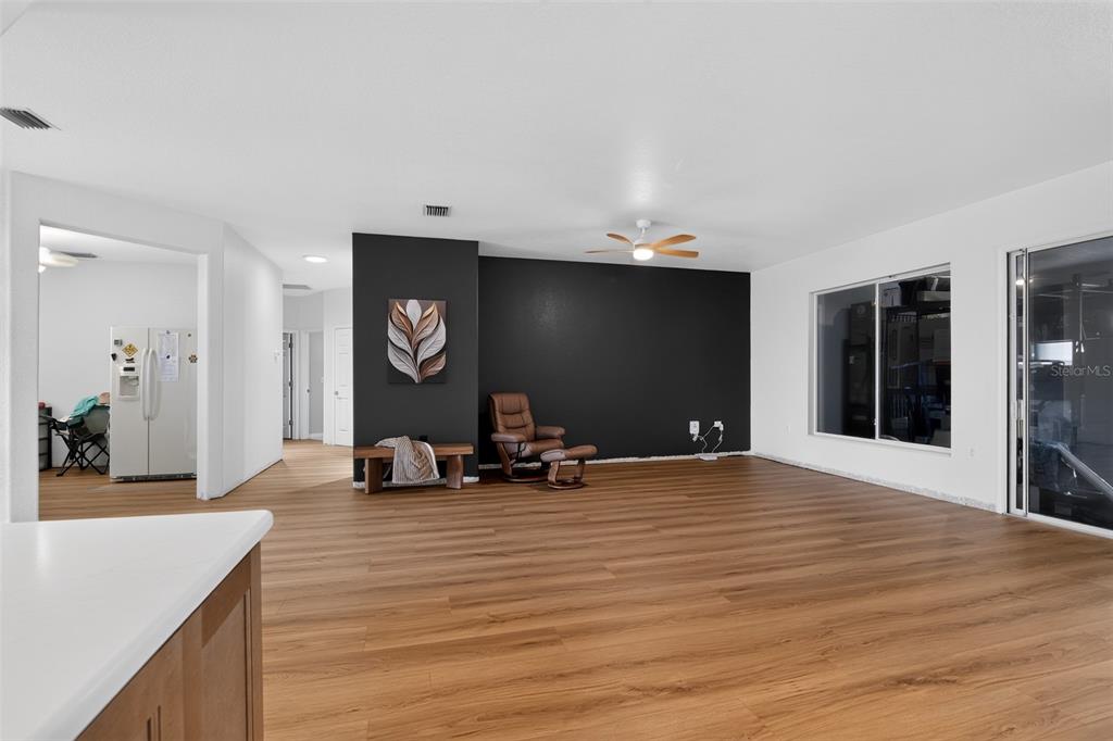 A spacious living room features wood-look flooring, a black accent wall, and a ceiling fan — 9415 SE 125TH STREET, SUMMERFIELD, FL