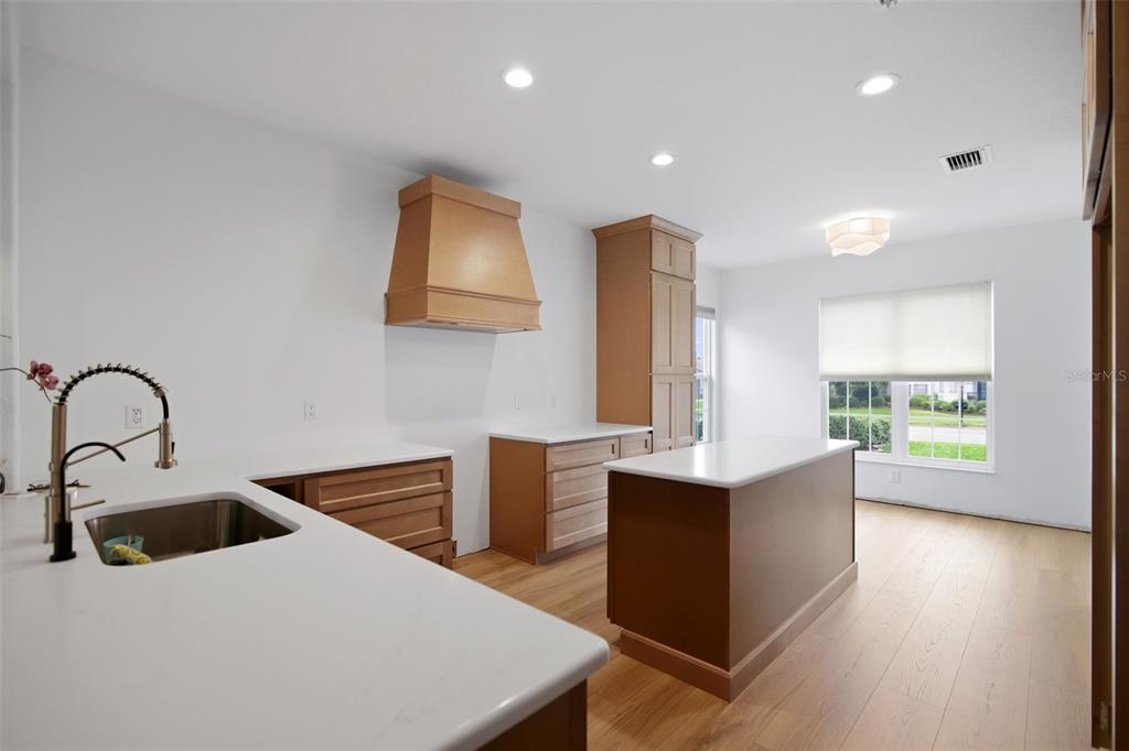 A kitchen with wood cabinets, white countertops, a center island, and light wood flooring — 9415 SE 125TH STREET, SUMMERFIELD, FL