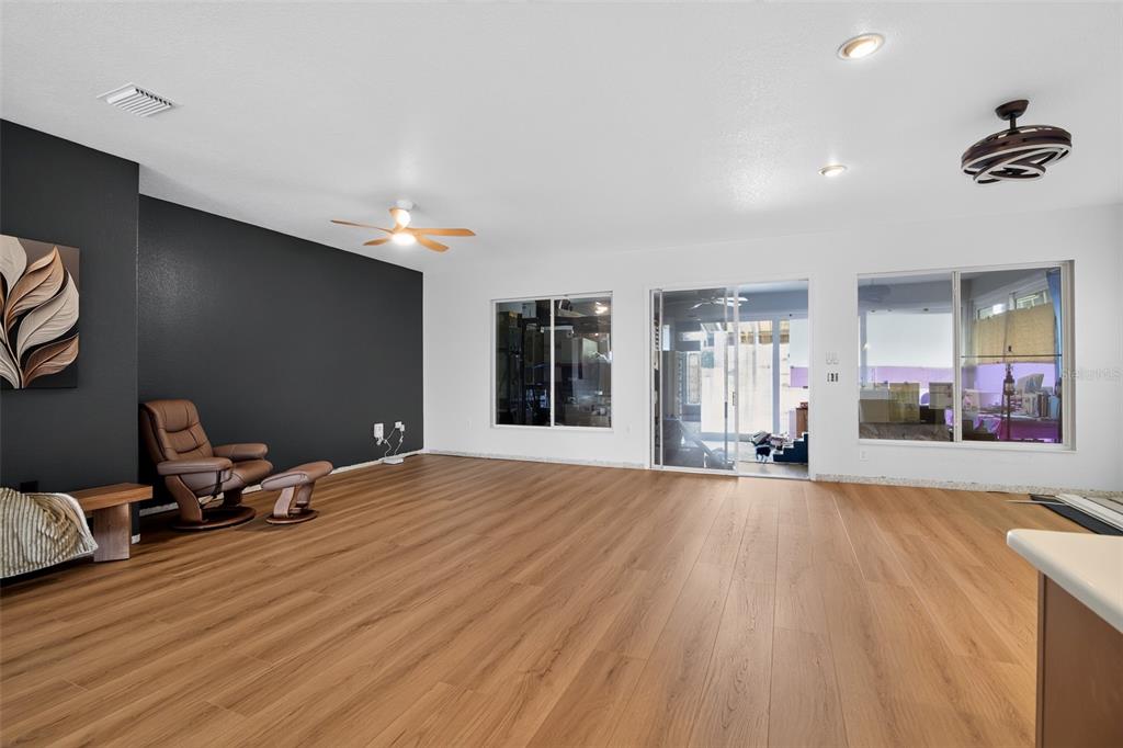 A spacious living room features wood-look flooring, a dark accent wall, and sliding glass doors — 9415 SE 125TH STREET, SUMMERFIELD, FL