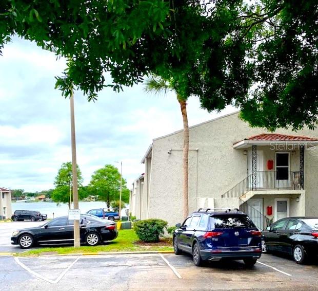 A parking lot sits in front of a multi-story apartment building near a lake — 1103 CYPRESS GARDENS BOULEVARD UNIT 13, WINTER HAVEN, FL