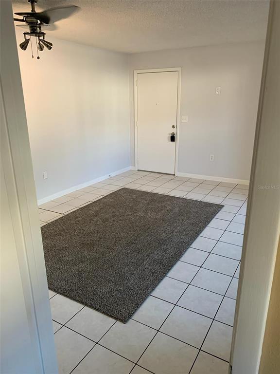 A room with white walls, a tiled floor, a gray area rug, and a ceiling fan — 1103 CYPRESS GARDENS BOULEVARD UNIT 13, WINTER HAVEN, FL