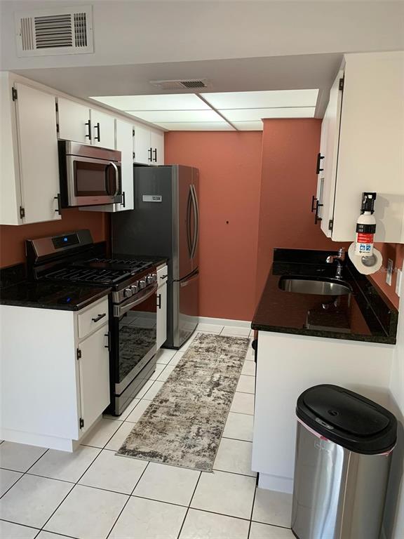 A kitchen features white cabinets, stainless steel appliances, dark countertops, and a tile floor — 1103 CYPRESS GARDENS BOULEVARD UNIT 13, WINTER HAVEN, FL