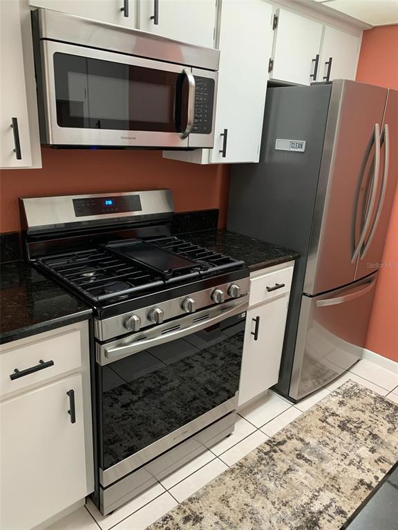 A kitchen features white cabinets, stainless steel appliances, and dark granite countertops — 1103 CYPRESS GARDENS BOULEVARD UNIT 13, WINTER HAVEN, FL