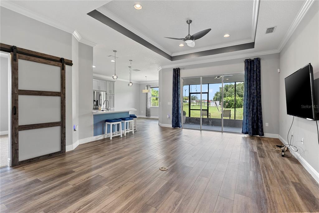 An entryway with wood-look flooring features a white front door and a sliding barn door — 8113 BRIDGEPORT BAY CIRCLE, MOUNT DORA, FL