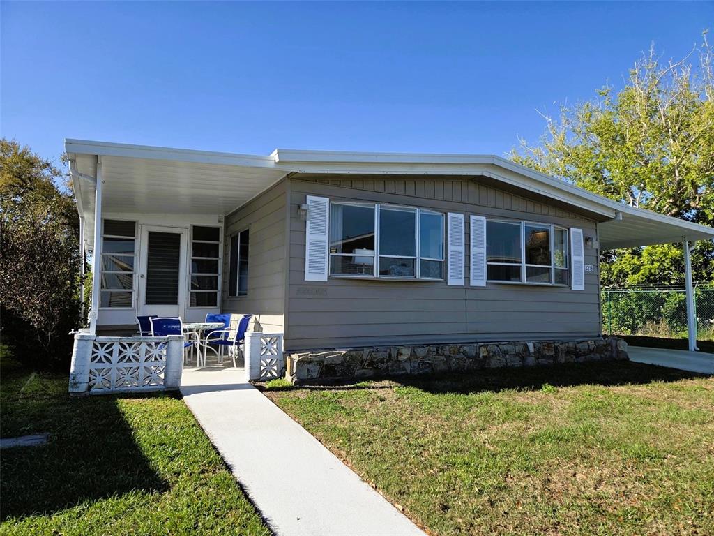 A single-story manufactured home with tan siding, a covered porch, and a stone foundation — 3218 OAKWOOD BOULEVARD S, SARASOTA, FL