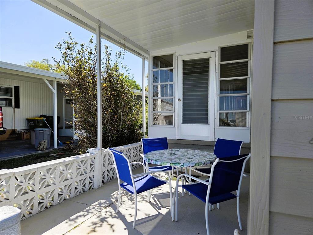 A covered patio features a round table with four blue chairs and a decorative wall — 3218 OAKWOOD BOULEVARD S, SARASOTA, FL