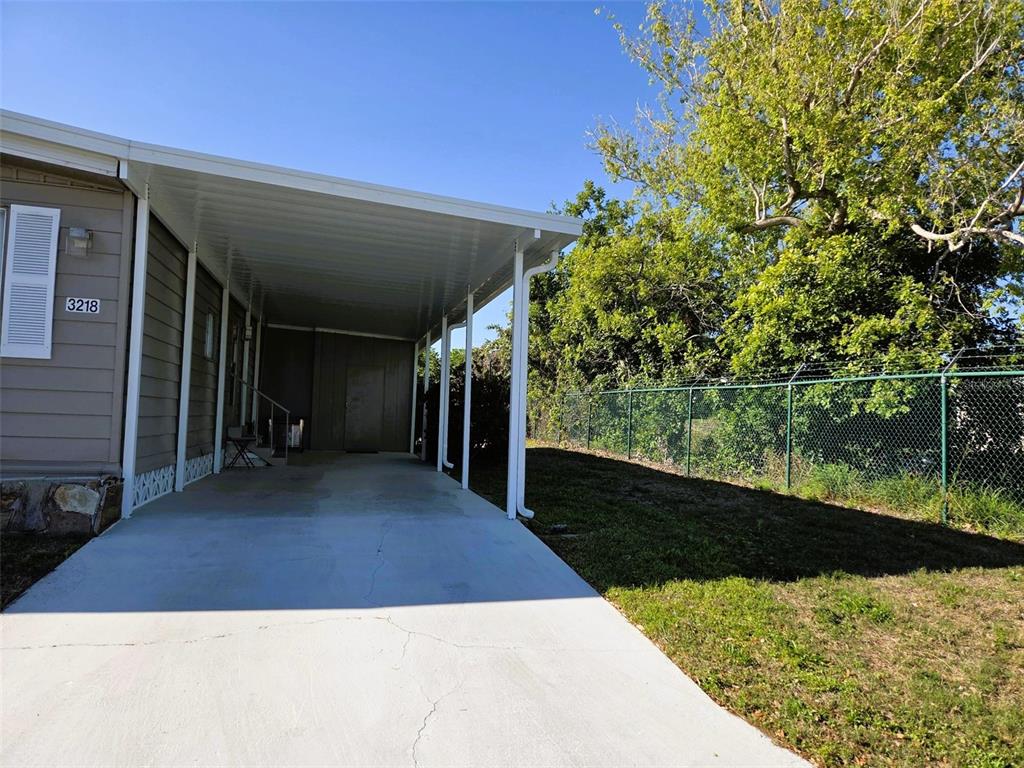 A concrete driveway leads to a covered carport attached to the side of a house — 3218 OAKWOOD BOULEVARD S, SARASOTA, FL