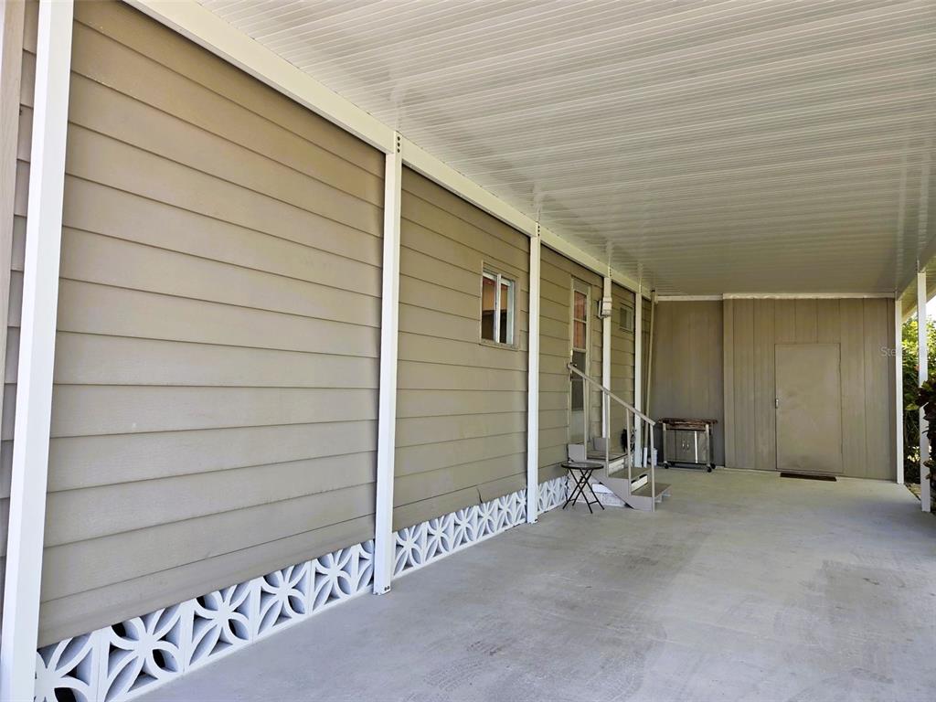 A covered carport area features beige horizontal siding, a concrete floor, and decorative lattice skirting — 3218 OAKWOOD BOULEVARD S, SARASOTA, FL