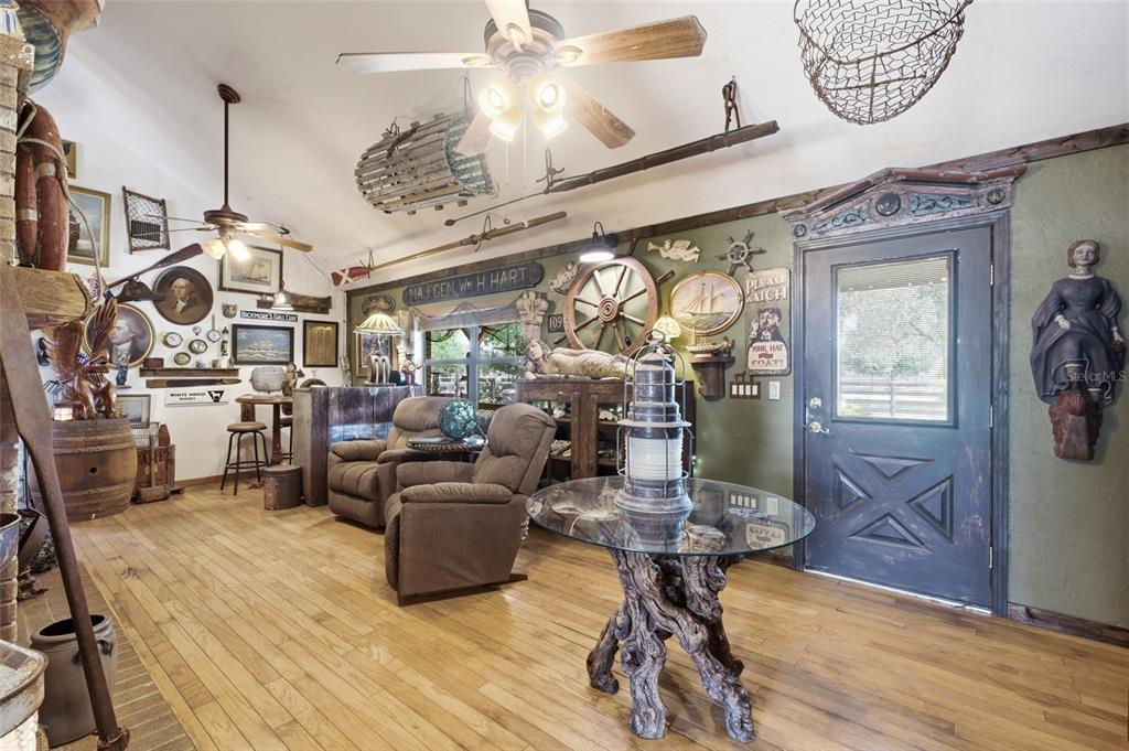 A nautical-themed room features hardwood floors, two recliners, a glass-topped table, and various maritime decor — 7674 SW ENVIRONMENTAL LAB STREET, ARCADIA, FL