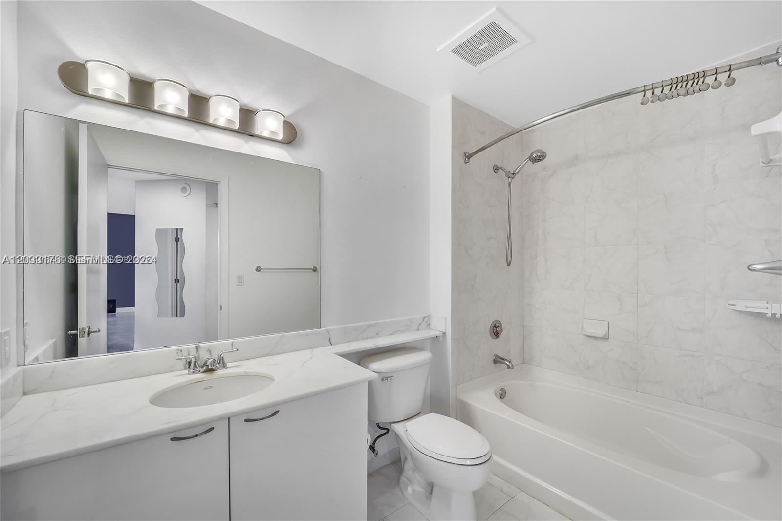 A bathroom features a white vanity, a toilet, and a bathtub with a shower head — 234 NE 3rd St # 507, Miami FL 33132, MIAMI, FL