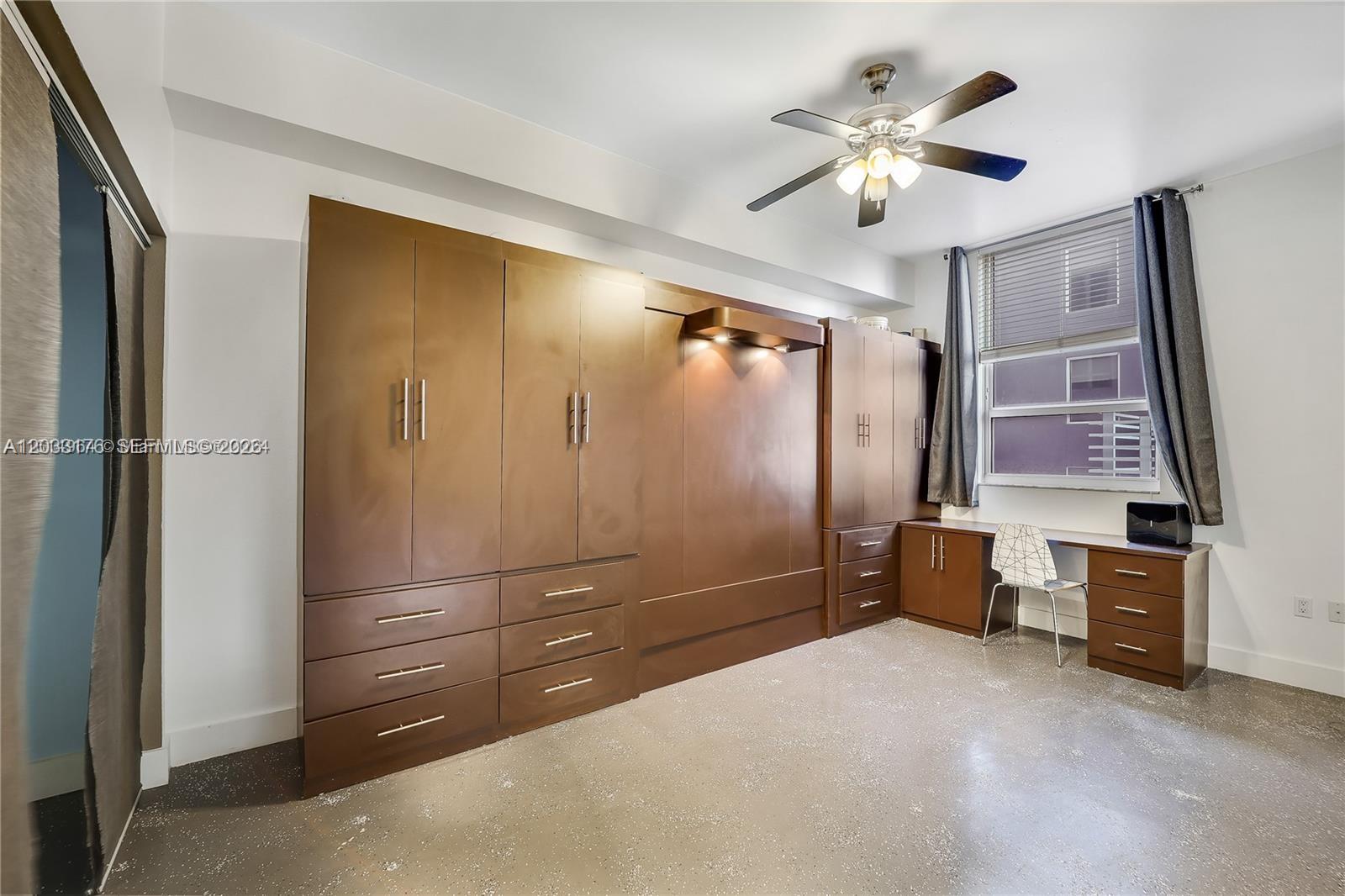 A bedroom features a large brown wall unit with a built-in desk and ceiling fan — 234 NE 3rd St # 507, Miami FL 33132, MIAMI, FL