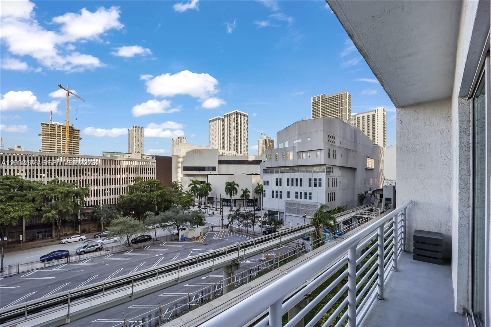 A balcony overlooks a parking lot, city streets, and surrounding high-rise buildings — 234 NE 3rd St # 507, Miami FL 33132, MIAMI, FL