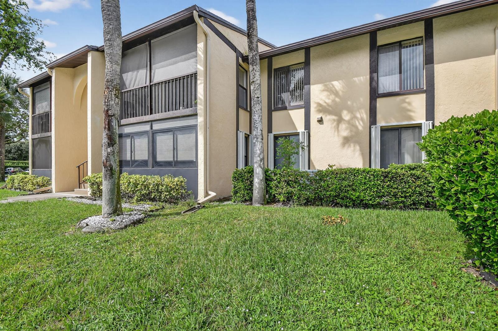 A two-story apartment building with tan stucco walls, dark trim, and screened-in balconies — 815 Sky Pine Way # B1, FL 33415, FL
