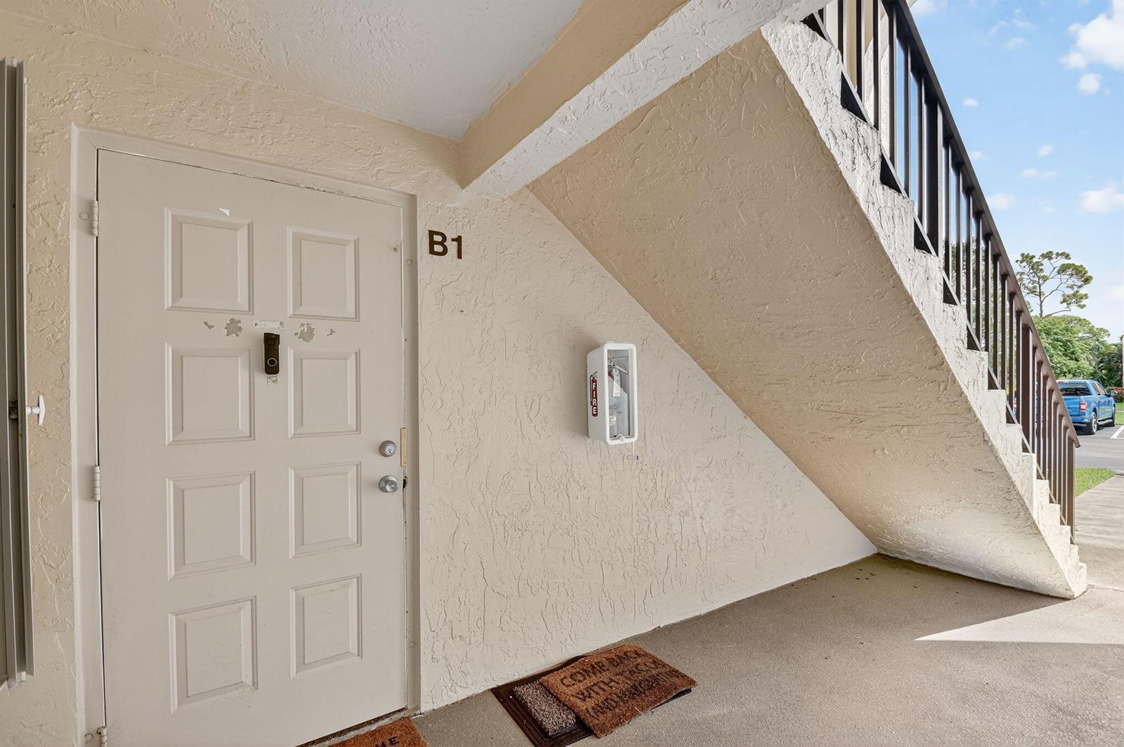 The exterior entrance to apartment B1 features a white door, a fire extinguisher, and stairs — 815 Sky Pine Way # B1, FL 33415, FL