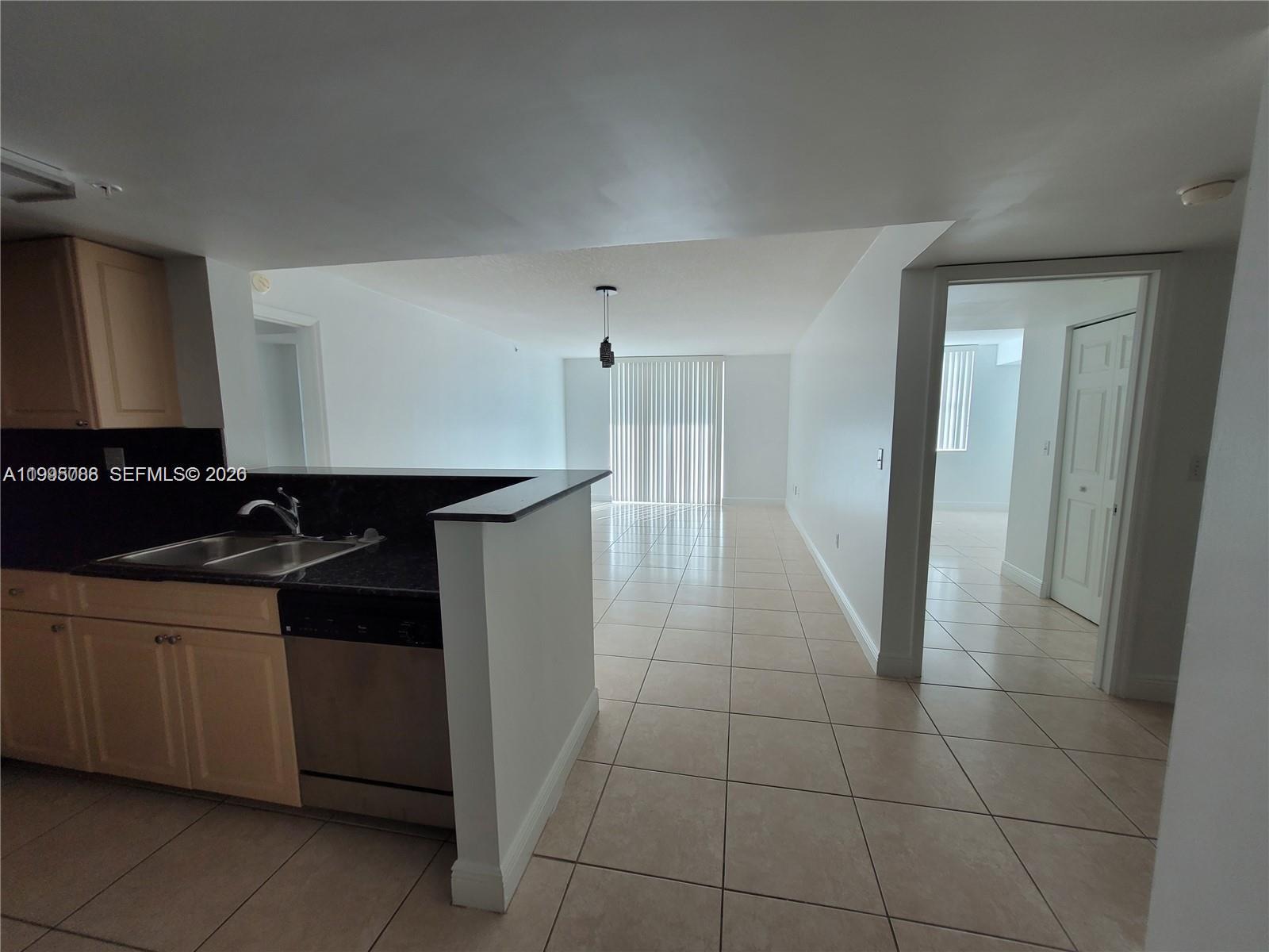 A kitchen with light wood cabinets and dark countertops opens into a tiled living area — 3000 Coral Way # 1512, Miami FL 33145, MIAMI, FL