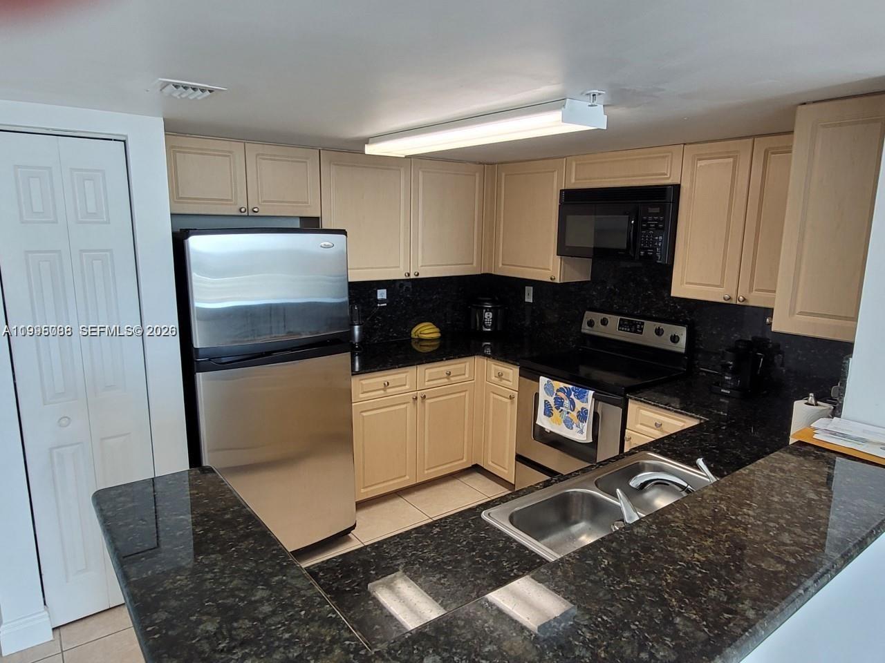 A kitchen features light wood cabinets, dark granite countertops, and stainless steel appliances — 3000 Coral Way # 1512, Miami FL 33145, MIAMI, FL