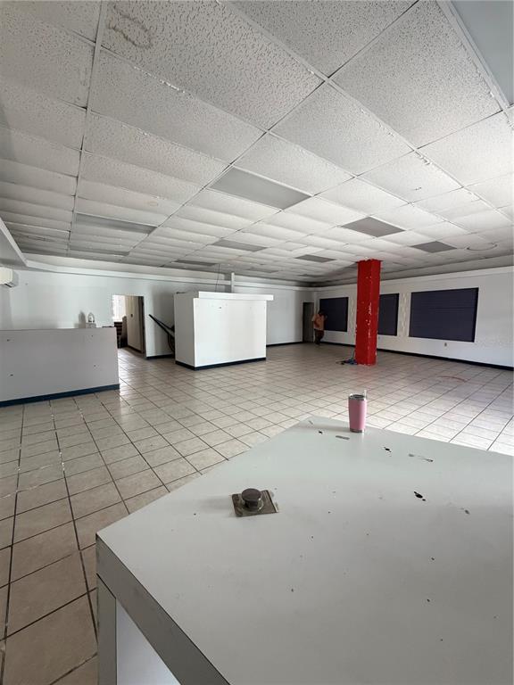 An open commercial space features white tiled floors, a drop ceiling, and a red pillar — 179 AVE JOSE DE DIEGO, ARECIBO, PR