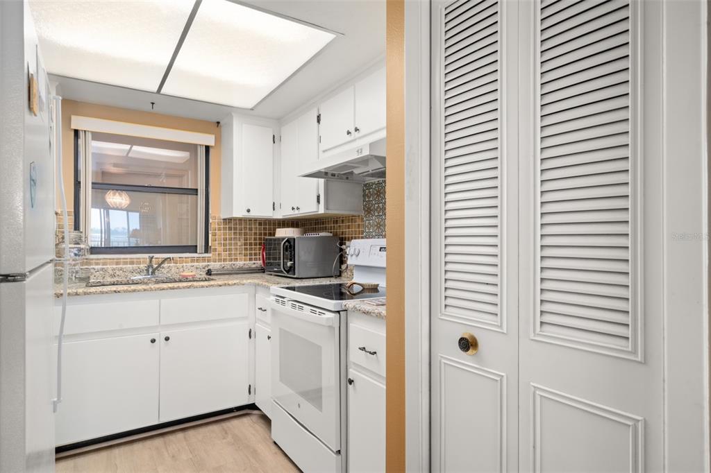 A kitchen with white cabinets, granite countertops, a tiled backsplash, and white appliances — 117 COUNTRY CLUB DRIVE UNIT 202, LAKE PLACID, FL