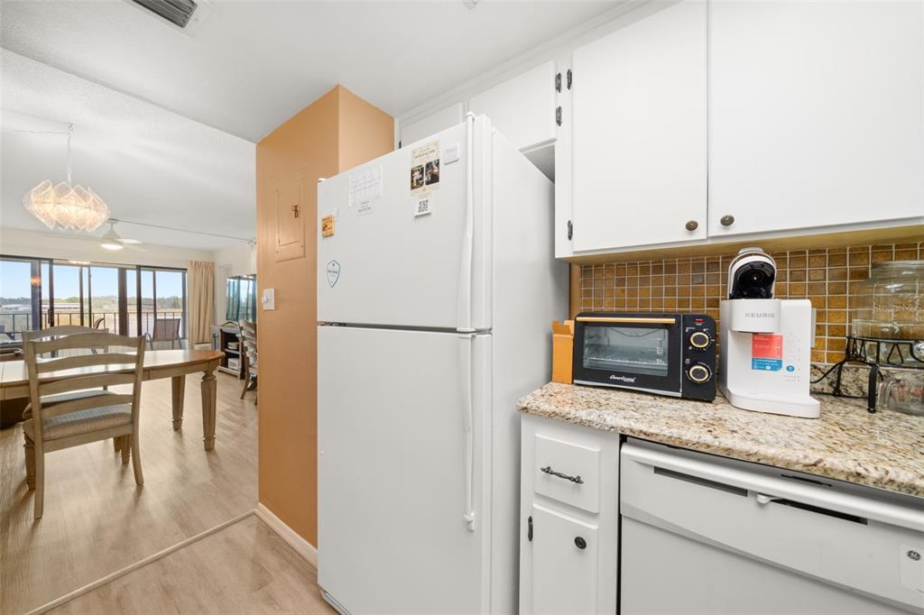 A kitchen features white cabinets, a granite countertop, a refrigerator, and a small toaster oven — 117 COUNTRY CLUB DRIVE UNIT 202, LAKE PLACID, FL