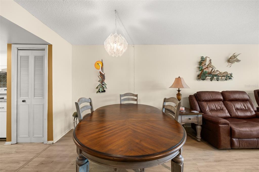 A dining area features a wooden table, three chairs, a pendant light, and a sofa — 117 COUNTRY CLUB DRIVE UNIT 202, LAKE PLACID, FL