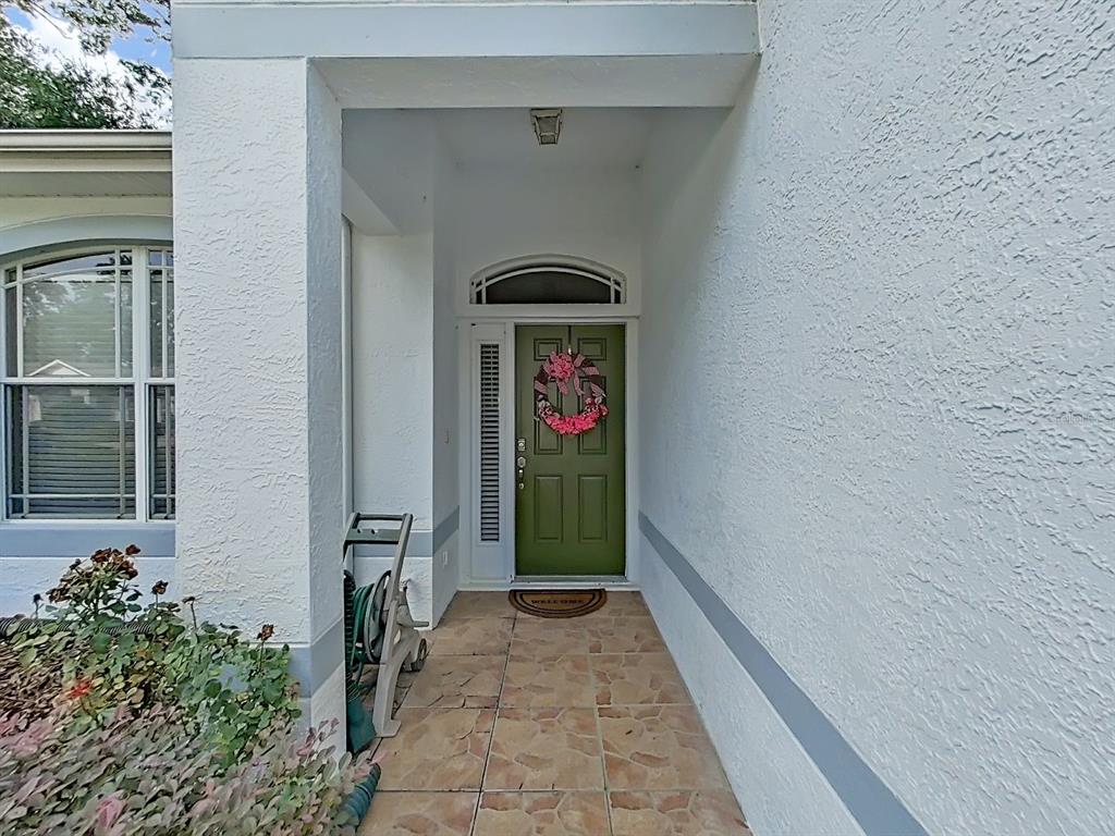 A covered entryway features a green front door with a wreath and tiled flooring — 8609 ALEXANDRA ARBOR LANE, TEMPLE TERRACE, FL