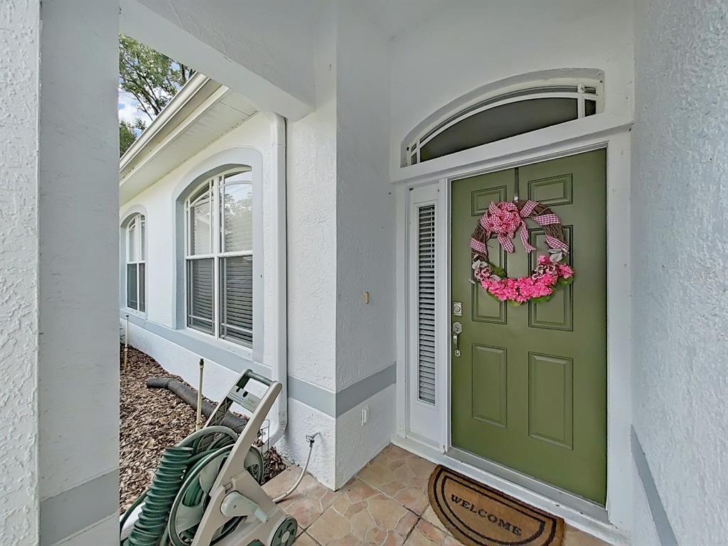 A green front door with a floral wreath is set within a white stucco entryway — 8609 ALEXANDRA ARBOR LANE, TEMPLE TERRACE, FL