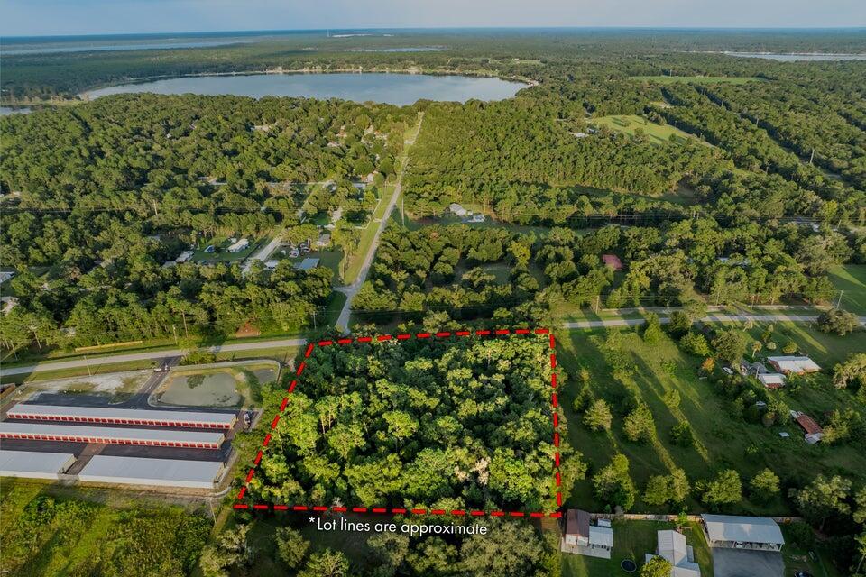An aerial view shows a wooded, rectangular lot outlined in red next to storage buildings — 0000 SE 9th Avenue, Starke FL 32091, STARKE, FL