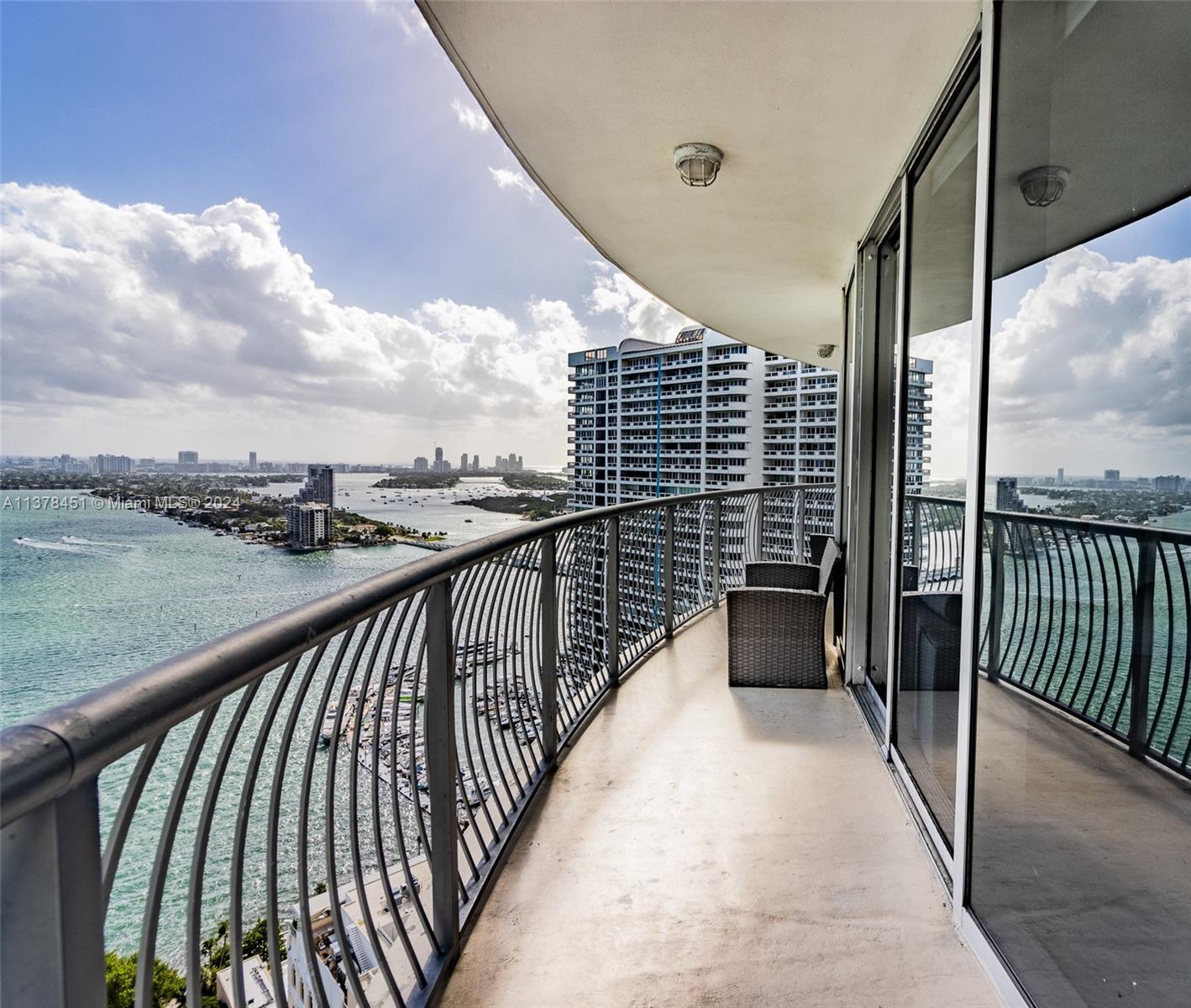 A curved balcony overlooks a bay with a city skyline and a large residential building — 1750 N Bayshore Dr # 3201, Miami FL 33132, MIAMI, FL
