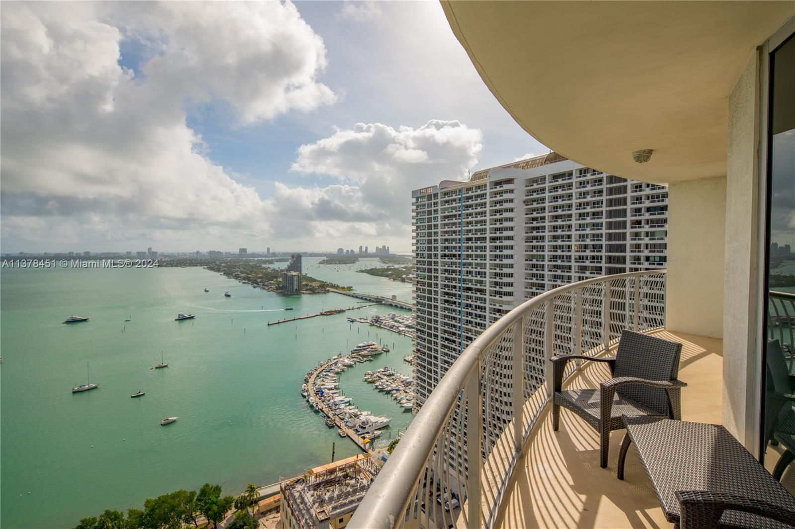 A high-rise balcony features outdoor furniture overlooking a bay with a marina and city skyline — 1750 N Bayshore Dr # 3201, Miami FL 33132, MIAMI, FL