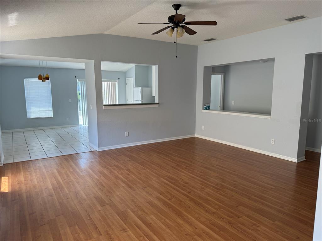 A living room with wood-look flooring, a ceiling fan, and two wall cutouts — 10925 SUBTLE TRAIL DRIVE, RIVERVIEW, FL