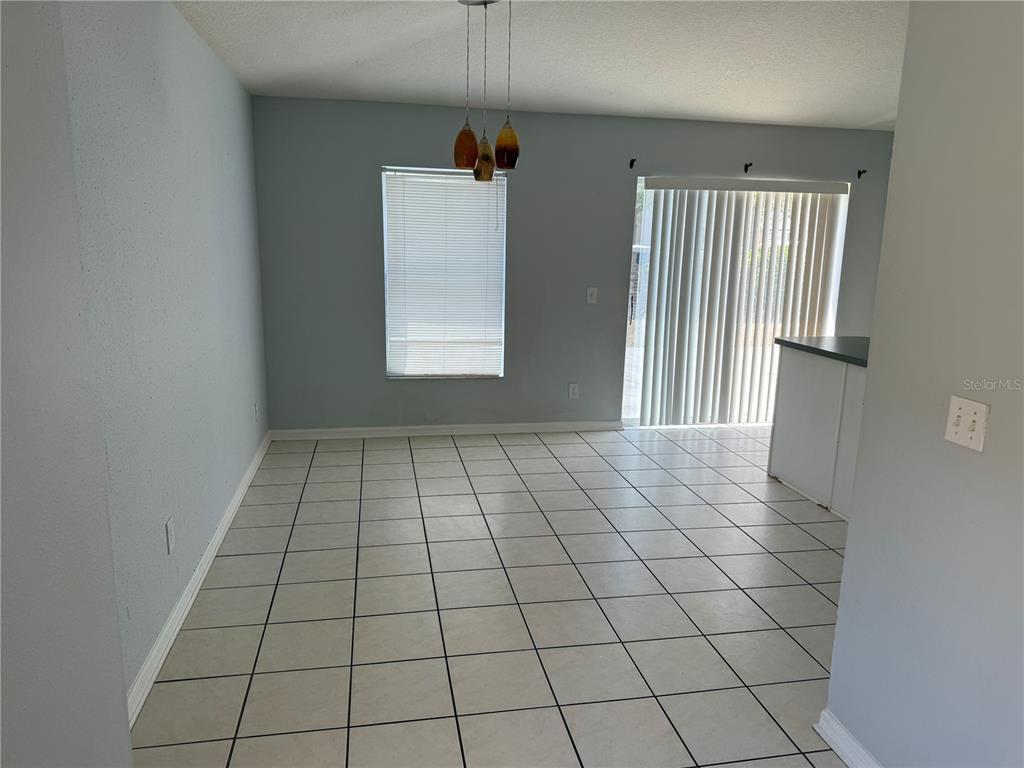 A dining area with light blue walls, white tile floors, a pendant light, and sliding doors — 10925 SUBTLE TRAIL DRIVE, RIVERVIEW, FL