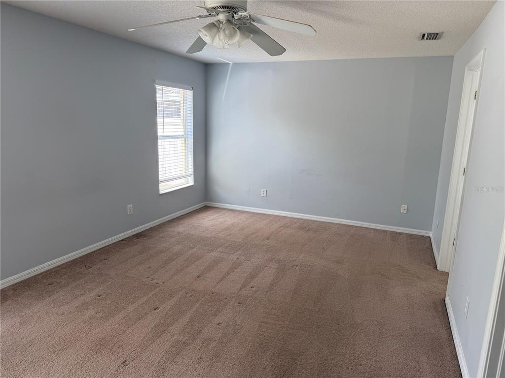 An empty bedroom features light blue walls, brown carpeting, a ceiling fan, and a window — 10925 SUBTLE TRAIL DRIVE, RIVERVIEW, FL