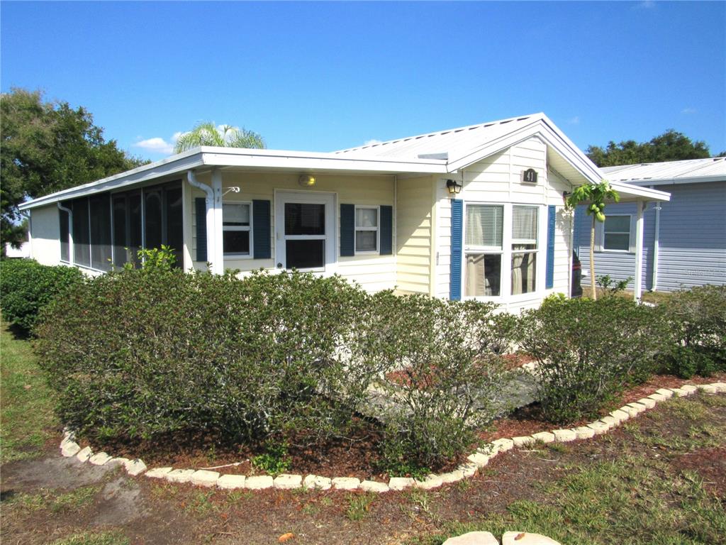 A single-story manufactured home with a screened porch, light siding, and a landscaped front yard — 50989 US HWY 27 UNIT 41, DAVENPORT, FL
