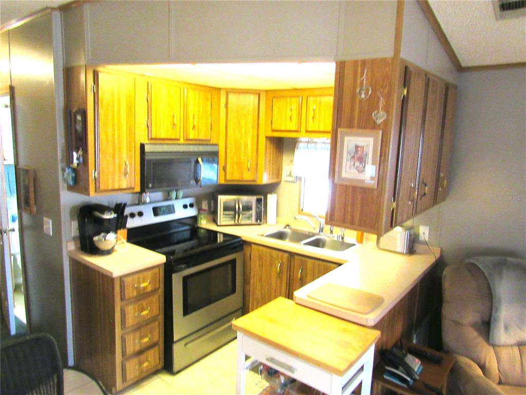 A kitchen features wood cabinets, stainless steel appliances, and a double sink with laminate countertops — 50989 US HWY 27 UNIT 41, DAVENPORT, FL