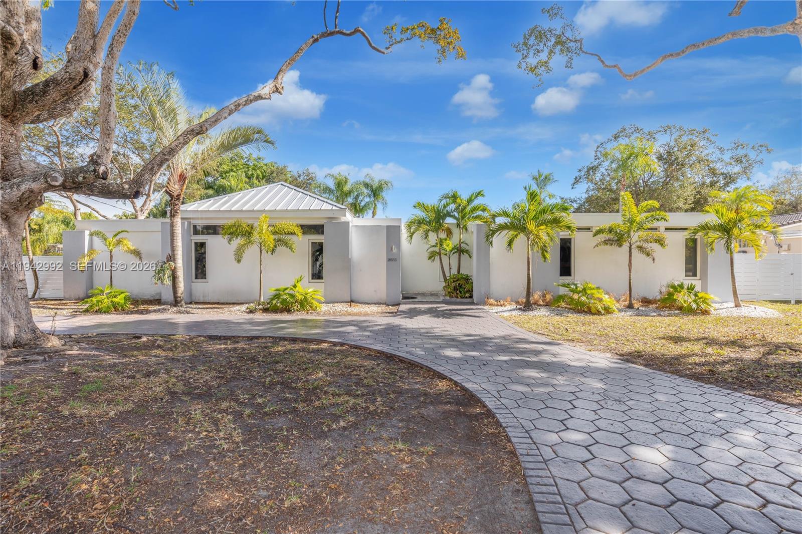 A white single-story house features a paved driveway, palm trees, and a metal roof — 18555 SW 83rd Pl, Cutler Bay FL 33157, CUTLER BAY, FL