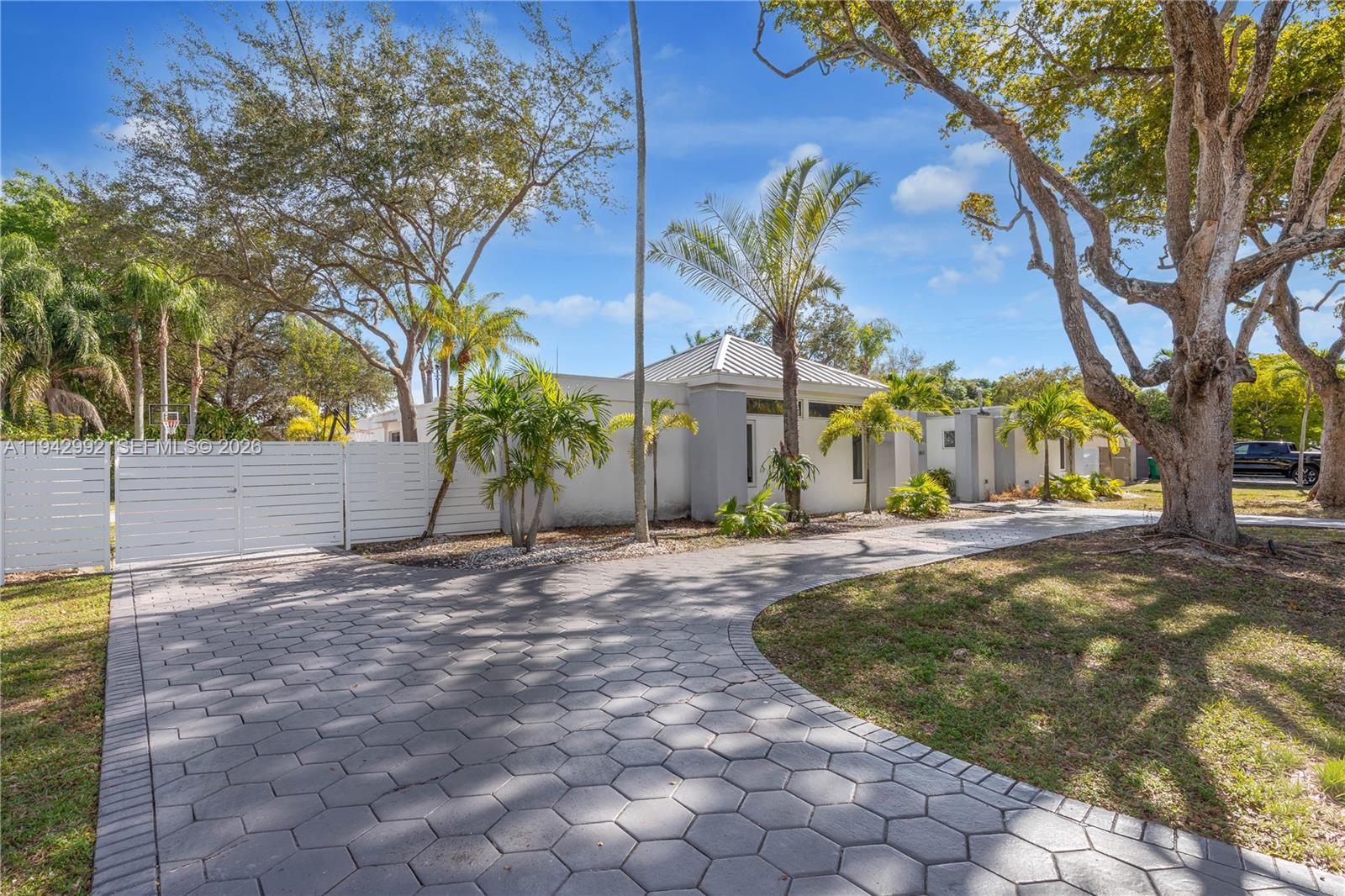 A paved driveway leads to a modern, light-colored house surrounded by palm trees and landscaping — 18555 SW 83rd Pl, Cutler Bay FL 33157, CUTLER BAY, FL