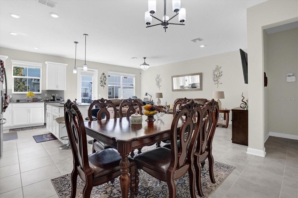 A dining area with a dark wood table and chairs sits adjacent to an open kitchen — 2909 THEME STREET, KISSIMMEE, FL