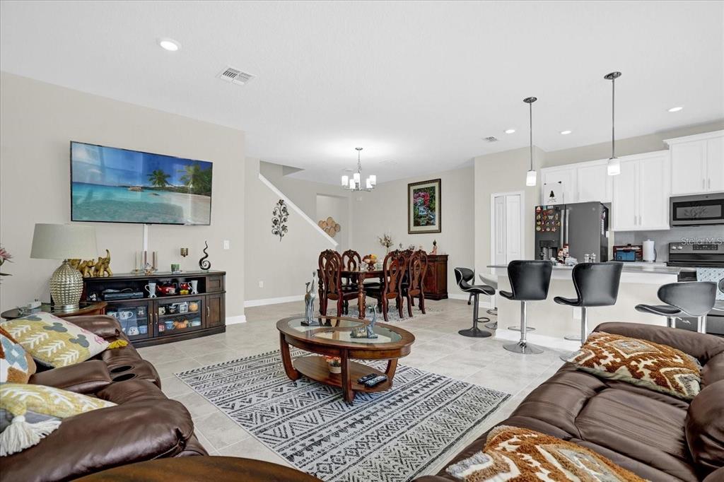 An open-concept living and dining area features tile flooring, a kitchen island, and brown furniture — 2909 THEME STREET, KISSIMMEE, FL