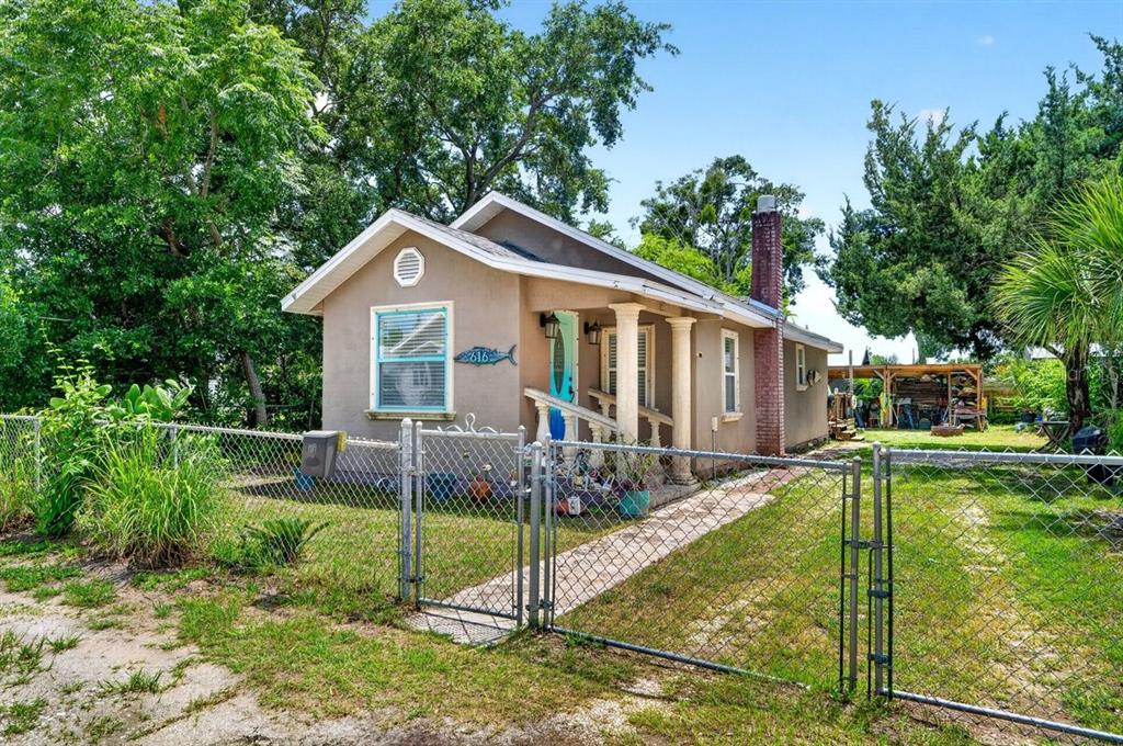 A small, single-story tan house with a front porch and chain-link fence — 616 DORA STREET, NEW SMYRNA BEACH, FL