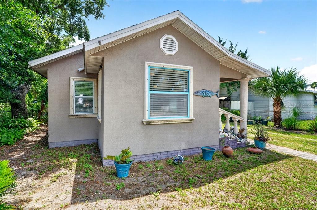 A small, tan-colored house with a front porch, blue window trim, and a fish-shaped sign — 616 DORA STREET, NEW SMYRNA BEACH, FL