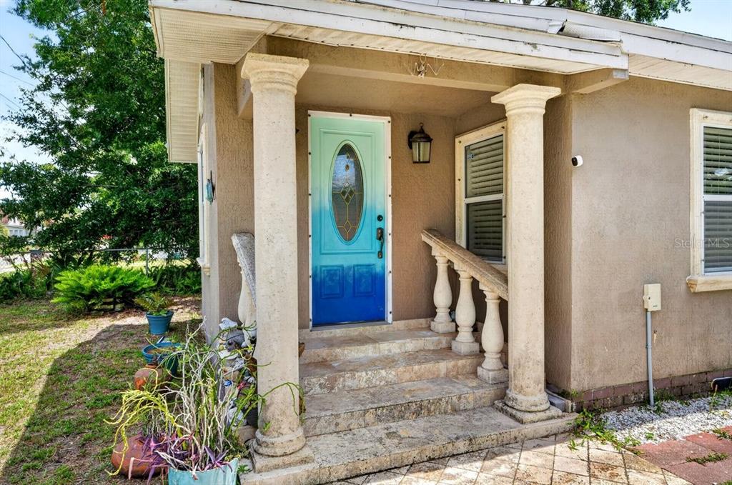 The front entrance features a blue ombre door, two stone columns, and tiled steps — 616 DORA STREET, NEW SMYRNA BEACH, FL