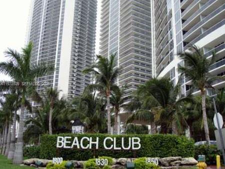 Tall residential towers rise behind a landscaped sign reading The Beach Club — 1800 Ocean Dr # 1408, Hallandale Beach FL 33009, HALLANDALE BEACH, FL